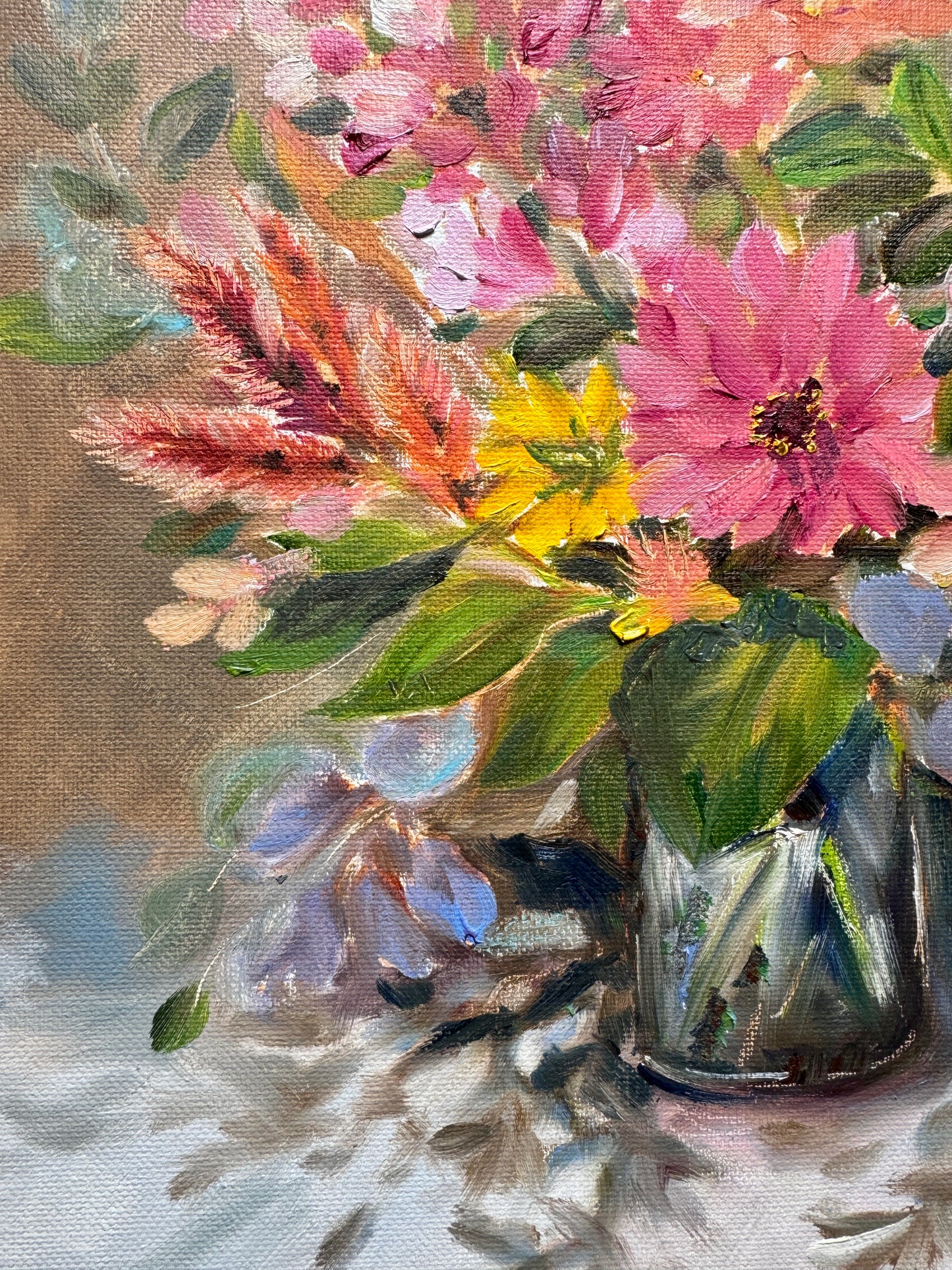Floral arrangement in a glass vase on a textured surface.