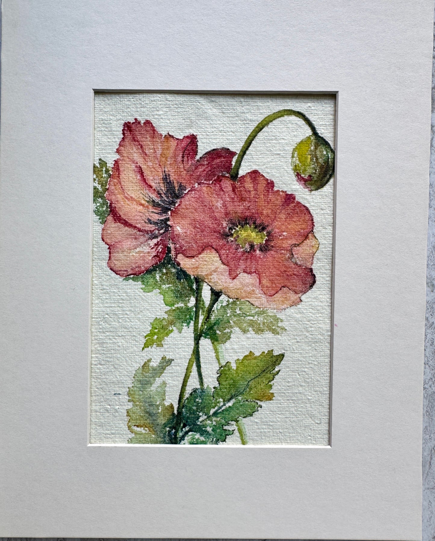 Framed artwork of pink flowers with green leaves on a textured gray background