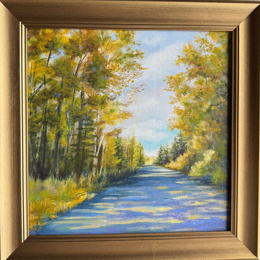 Oil painting of blue sky and a shaded path surrounded by trees with a gold frame. 